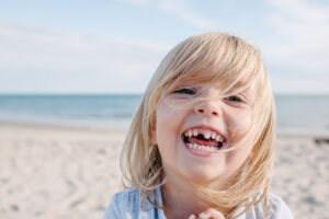 Blonde child with missing milk tooth laughing out loud